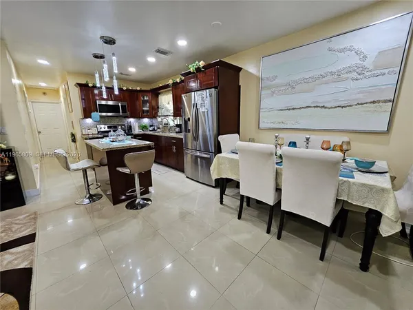 a living room with furniture and a dining table with kitchen appliances