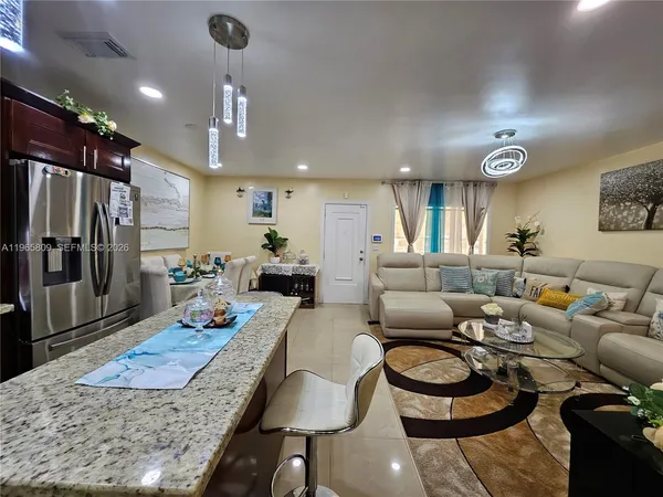 a living room with furniture a rug and kitchen view