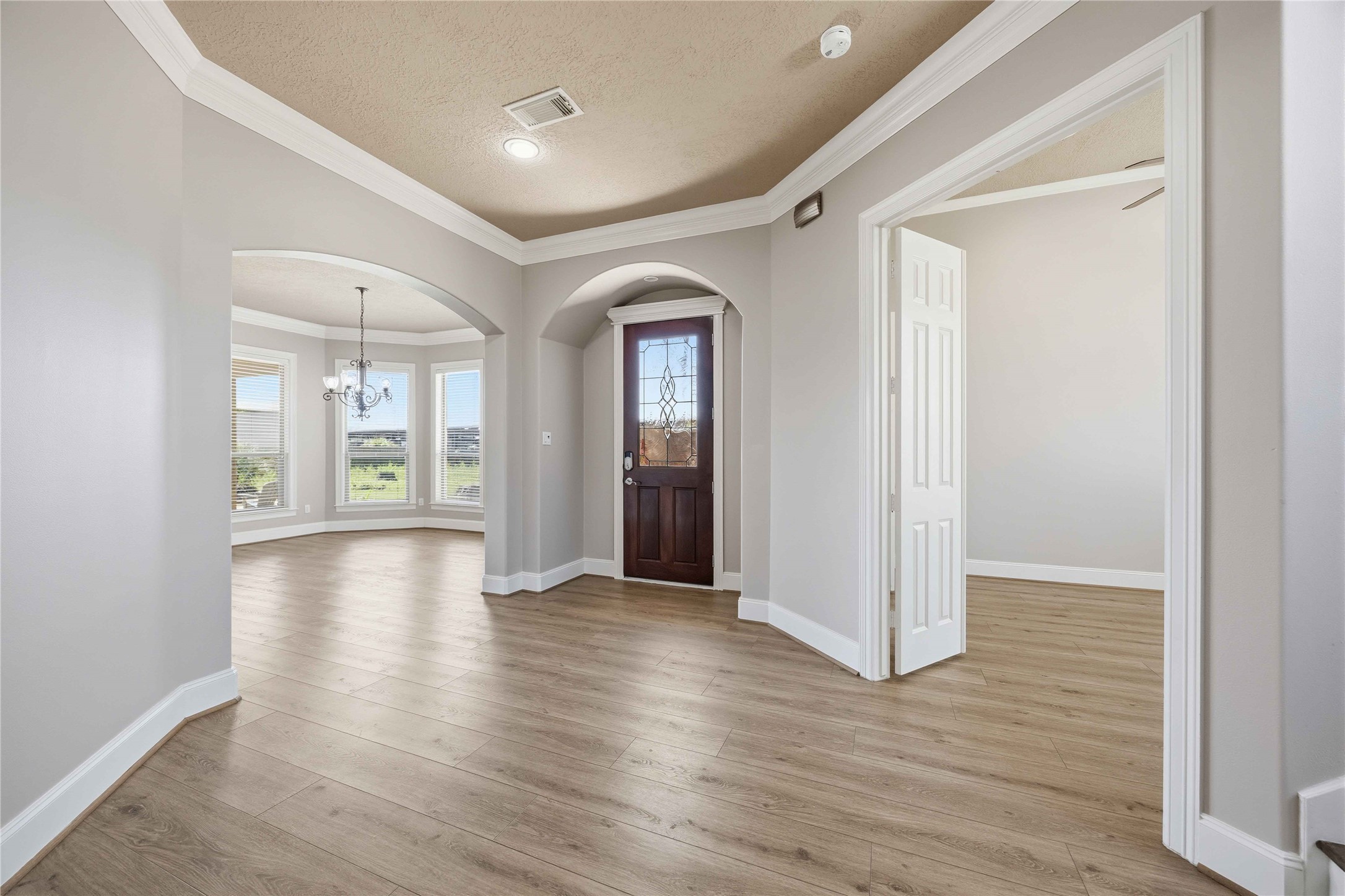 1930 Old River Road Montgomery, TX 77356 - Photo 6 of 49 High ceilings, Crown molding, sleek lines, and curved archways invite you inside. An abundance of natural light is reflected on the engineered wood floors that flow seamlessly throughout the first floor. As you enter the home, on your left is an ideal home office, or a 4th bedroom. (In this photo, it is on the right.) On the other side, you'll find the living room, dining room, and kitchen.