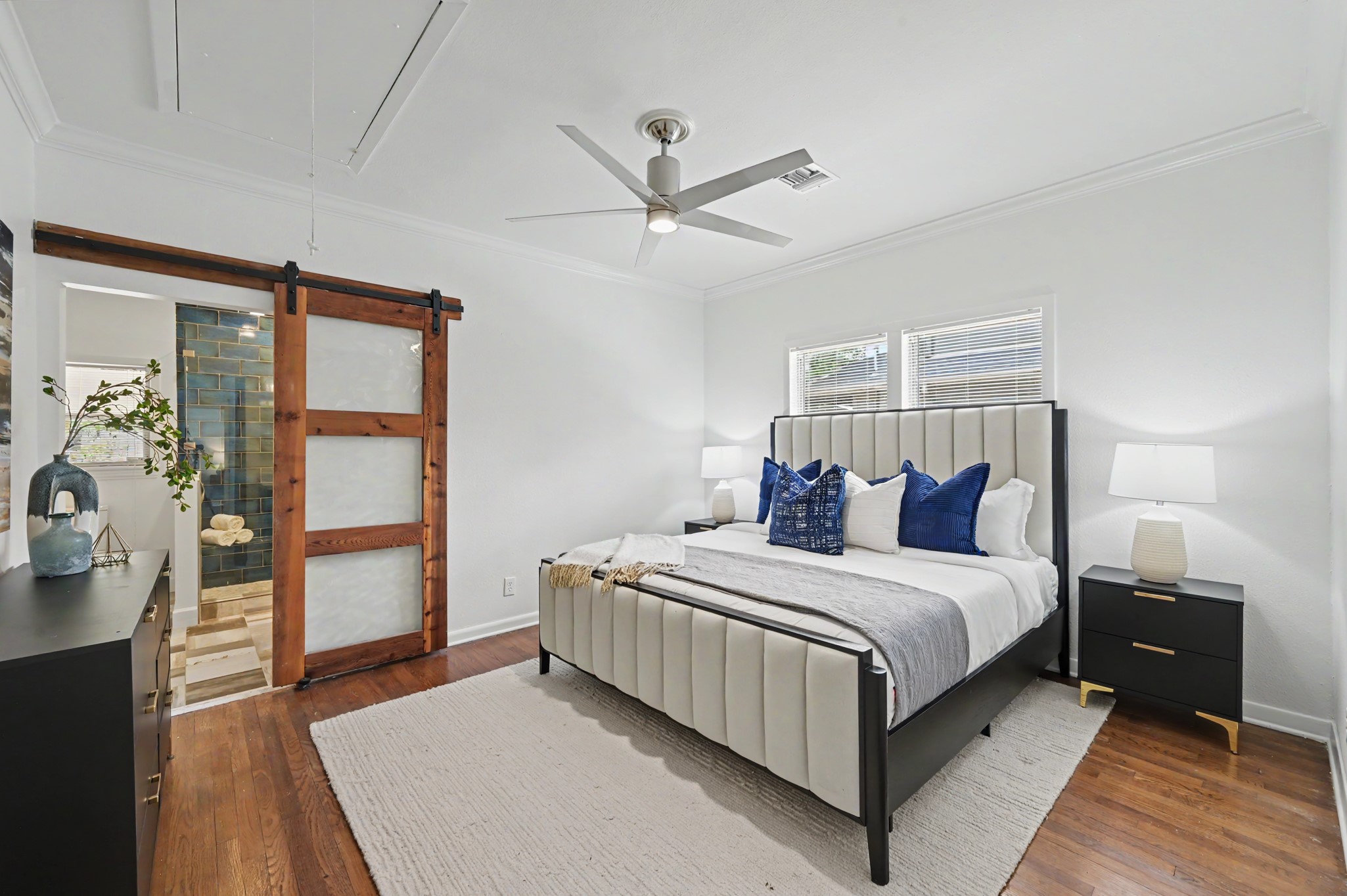 807 Key Street Houston, TX 77009 - Photo 15 of 27 Primary bedroom featuring hardwood floors, crown molding, ceiling fan, and a distinctive sliding barn door leading to the en-suite bath.