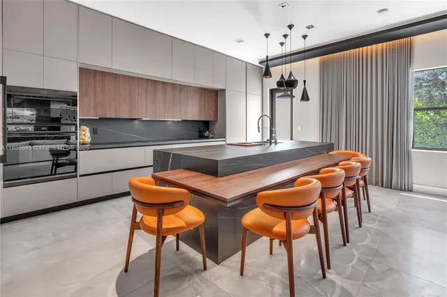 a kitchen with stainless steel appliances kitchen island granite countertop a table chairs sink and cabinets