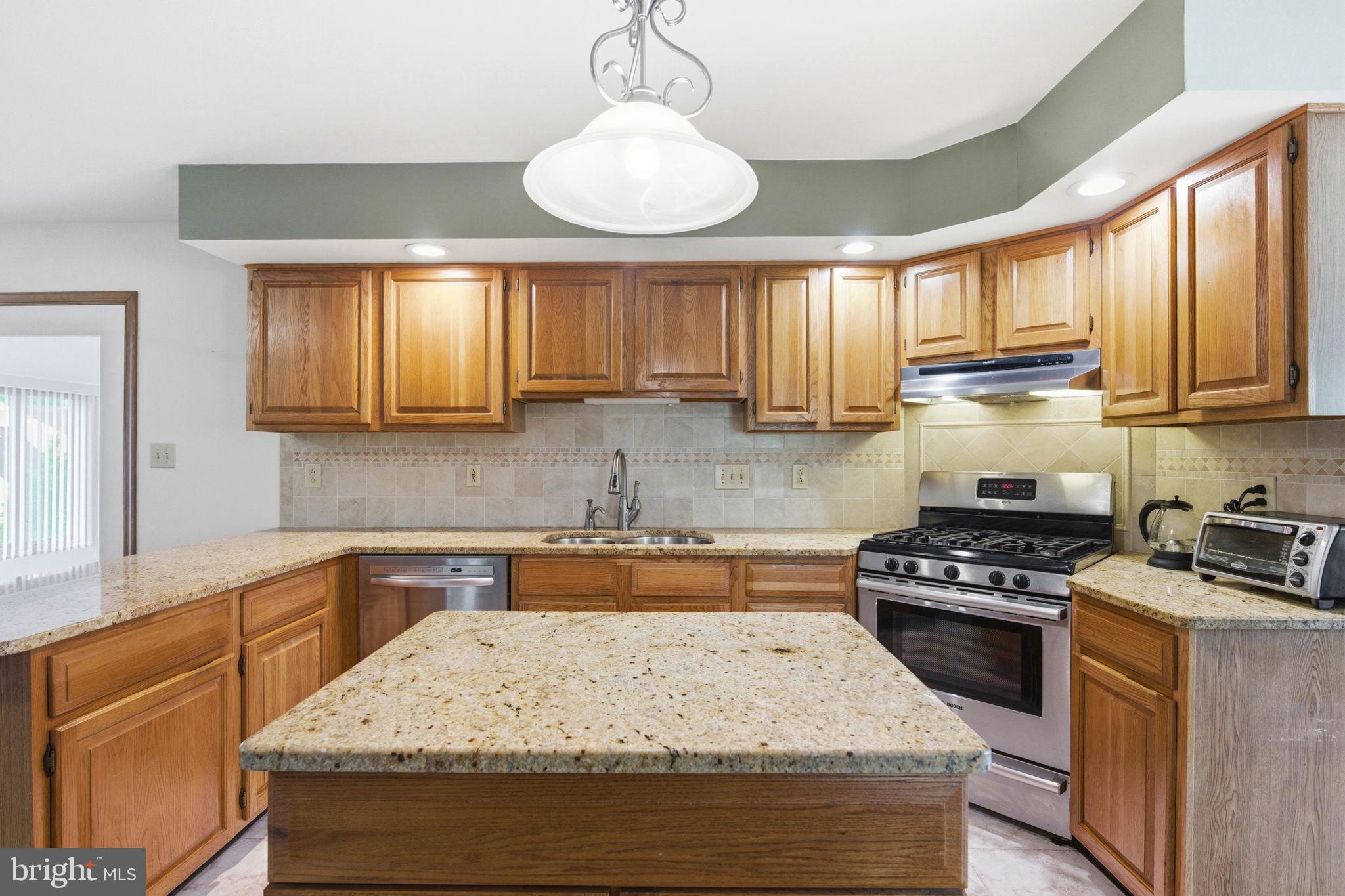 736 Letitia Drive Hockessin, DE 19707 - Photo 30 of 92 a kitchen with granite countertop wooden cabinets stove top oven and sink