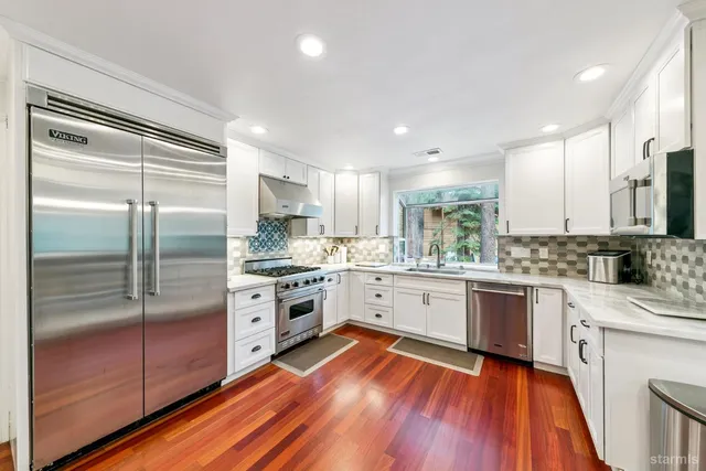 a large kitchen with cabinets wooden floor and stainless steel appliances