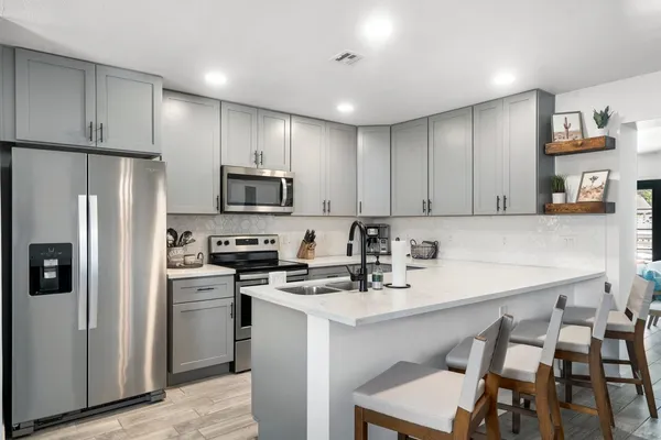 a kitchen with a sink a microwave a refrigerator and chairs