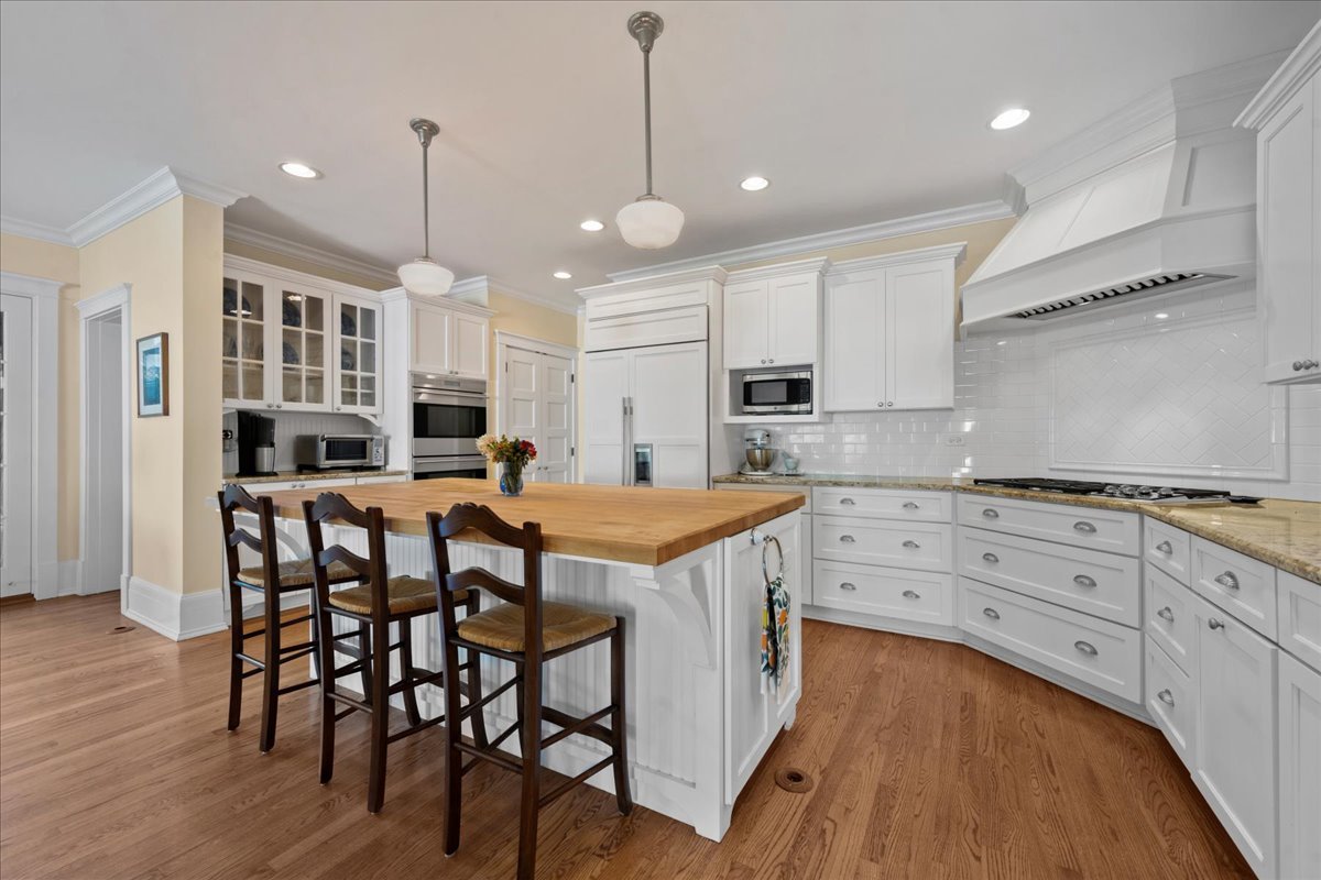 611 Ash Street Winnetka, IL 60093 - Photo 6 of 43 a kitchen with stainless steel appliances granite countertop a stove top oven a refrigerator a dining table and chairs with wooden floors