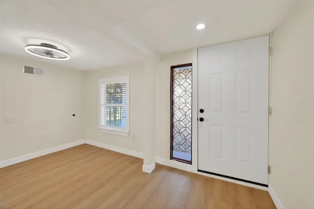 an empty room with wooden floor cabinet and windows