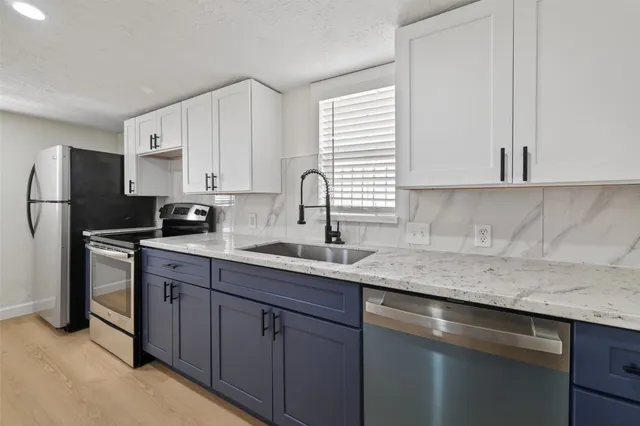 a kitchen with stainless steel appliances granite countertop a sink stove and refrigerator