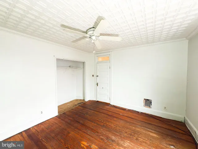 an empty room with wooden floor closet and windows