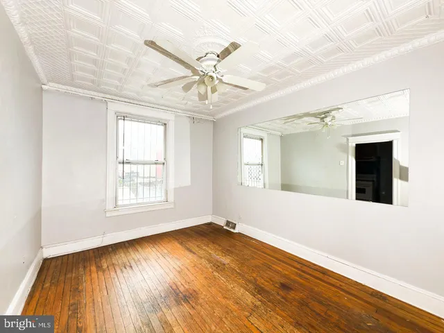 an empty room with wooden floor fan and windows