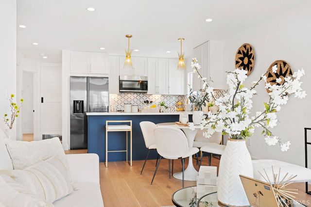 a kitchen with stainless steel appliances kitchen island granite countertop a refrigerator and a dining table