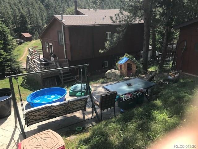 945 Wisp Creek Drive Bailey, CO 80421 - Photo 8 of 26 a backyard of a house with table and chairs potted plants
