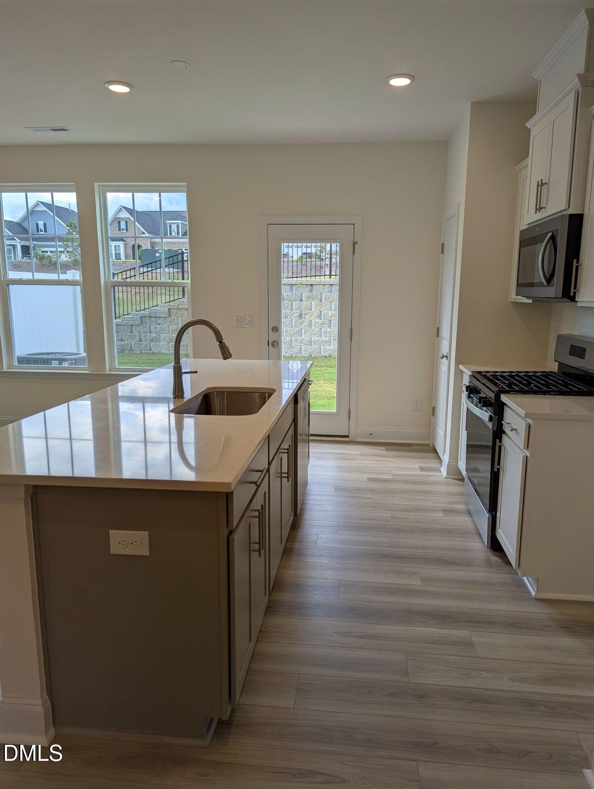 908 Kensley Grv Lane Fuquay-Varina, NC 27526 - Photo 14 of 37 a kitchen with kitchen island granite countertop a sink wooden floor and stainless steel appliances