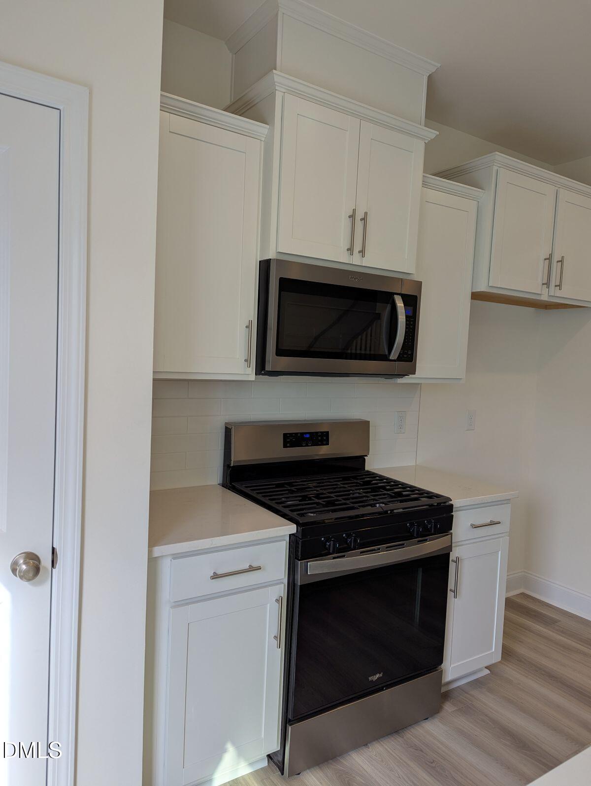 908 Kensley Grv Lane Fuquay-Varina, NC 27526 - Photo 15 of 37 a kitchen with white cabinets and black appliances
