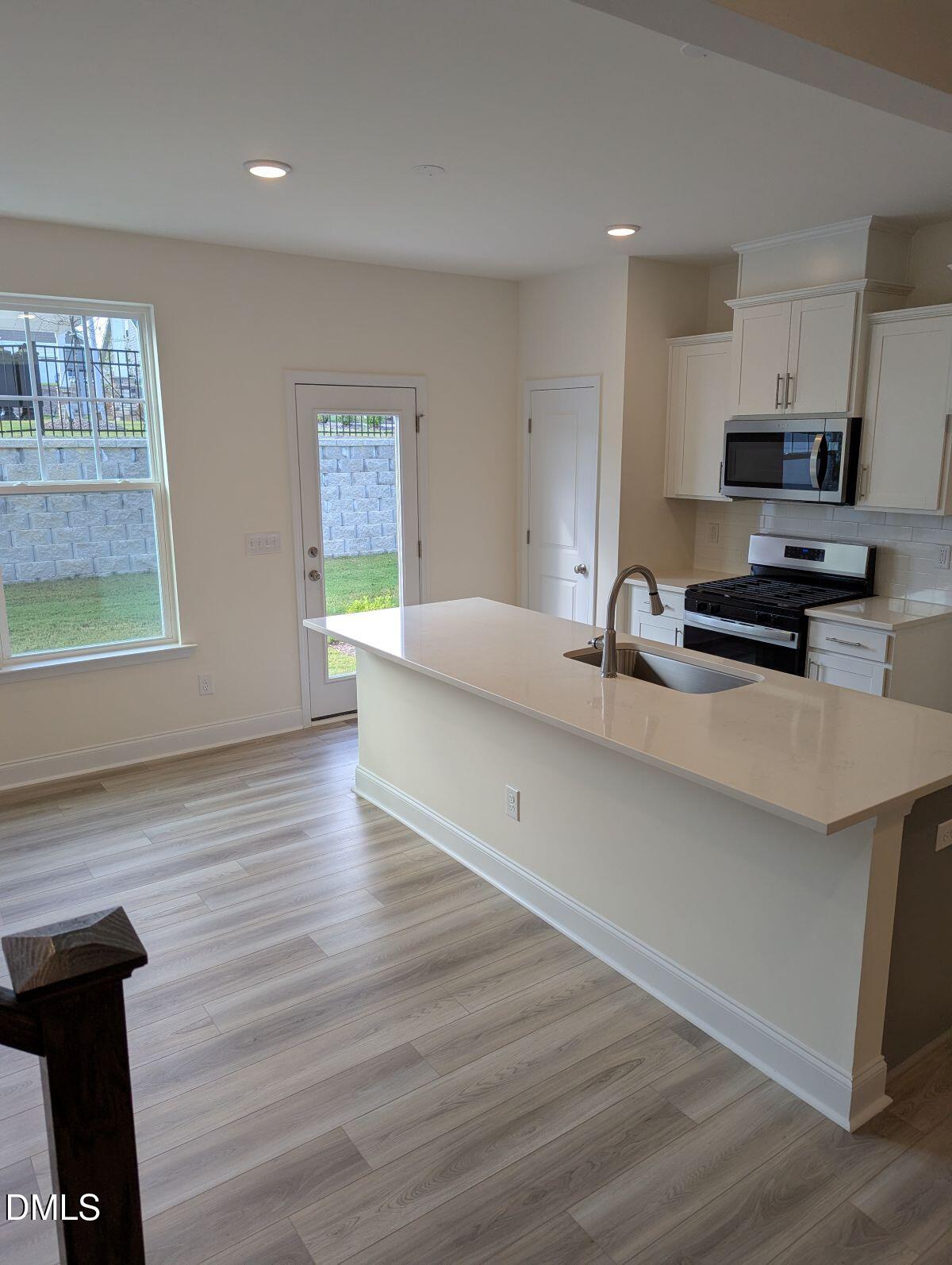 908 Kensley Grv Lane Fuquay-Varina, NC 27526 - Photo 8 of 37 a kitchen with stainless steel appliances a stove a sink a refrigerator white cabinets and wooden floor