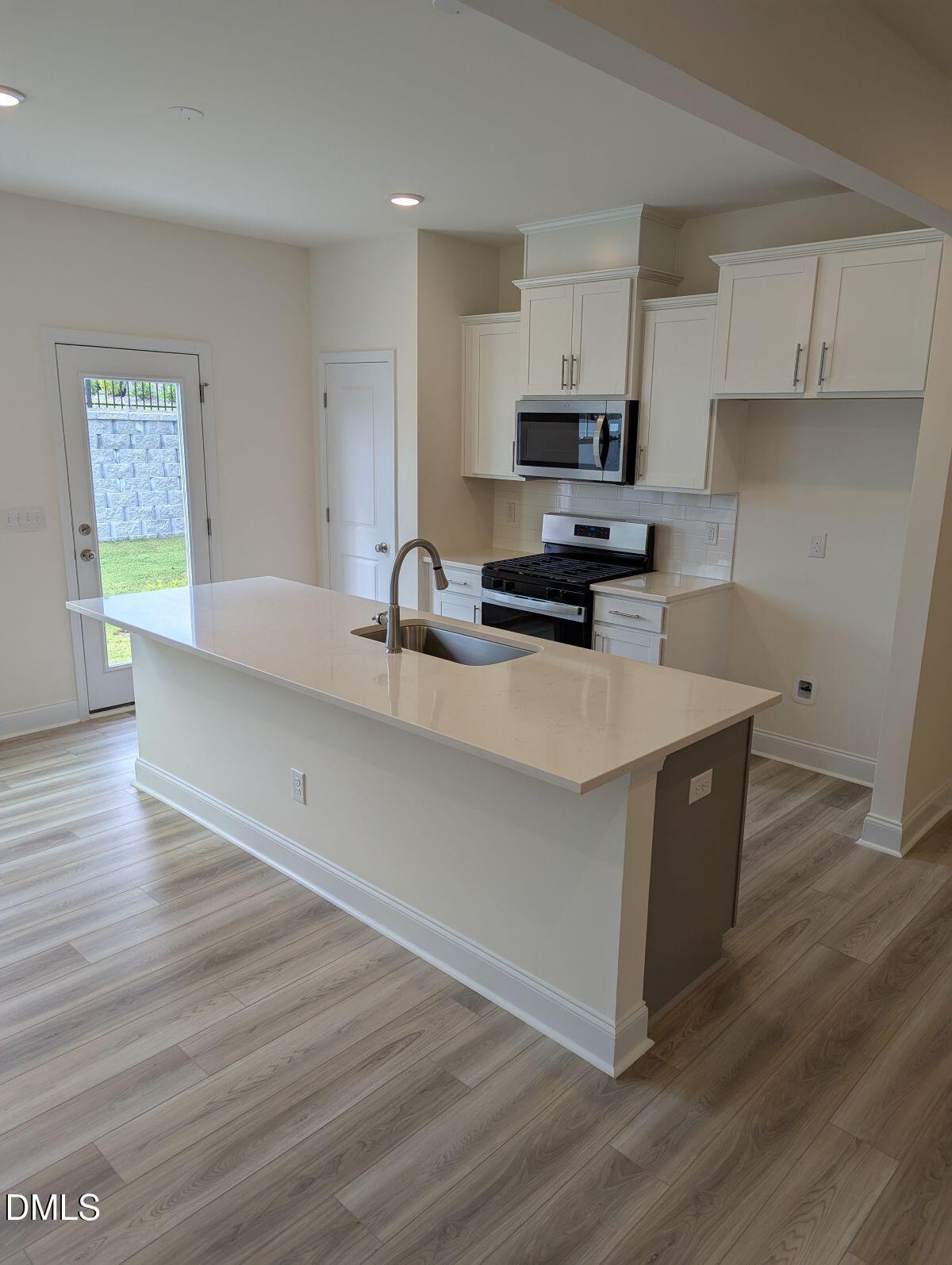 908 Kensley Grv Lane Fuquay-Varina, NC 27526 - Photo 10 of 37 a kitchen with stainless steel appliances a stove a sink a refrigerator white cabinets and wooden floor