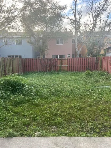 a view of a yard with wooden fence and a bench