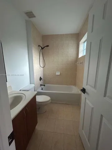 a bathroom with a granite countertop sink toilet mirror and bathtub