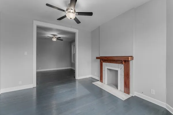 an empty room with wooden floor fan and windows