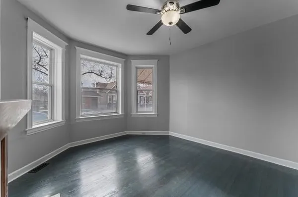 a view of an empty room with wooden floor and window