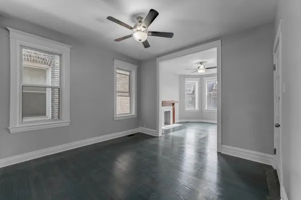 a view of empty room with wooden floor and fan