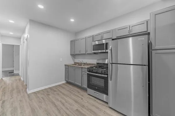 a kitchen with a refrigerator stove and wooden floor