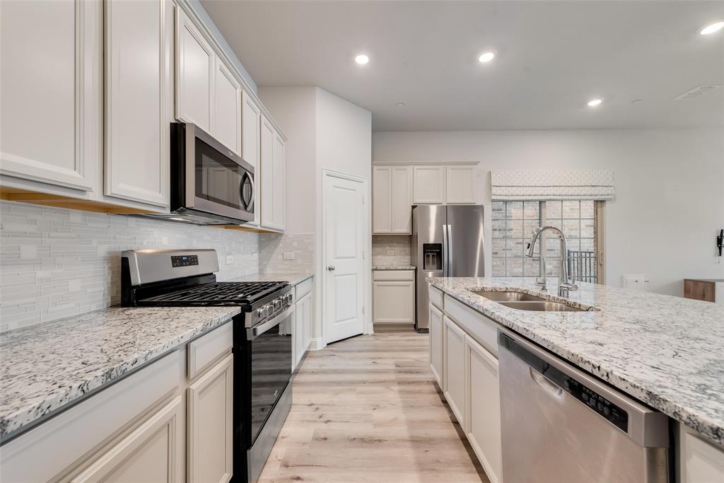 7617 Sunset Boulevard Rowlett, TX 75088 - Photo 11 of 21 Kitchen with appliances with stainless steel finishes, light wood-type flooring, light stone countertops, backsplash, and recessed lighting