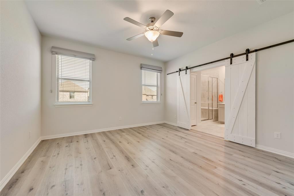 7617 Sunset Boulevard Rowlett, TX 75088 - Photo 15 of 21 Unfurnished bedroom featuring multiple windows, light wood-style flooring, a ceiling fan, and ensuite bath