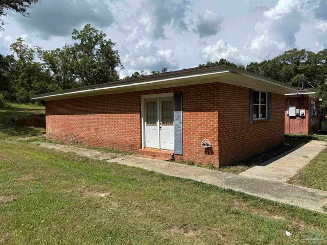 a view of house with yard and trees in the background