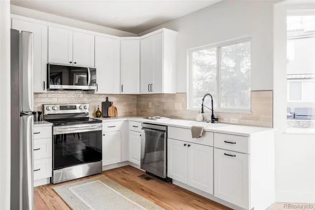 a kitchen with cabinets stainless steel appliances a sink and a window