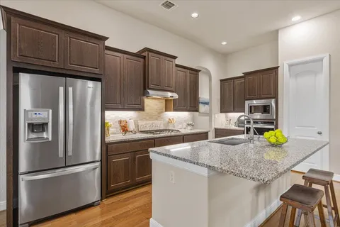 a kitchen with granite countertop a refrigerator a stove and wooden cabinets