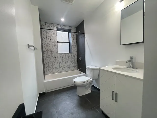 a bathroom with a toilet a sink a mirror a bathtub and vanity