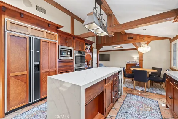 a utility room with stainless steel appliances kitchen island granite countertop a refrigerator a stove and a dining table with wooden floor