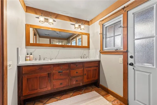 a bathroom with a sink a mirror and wooden cabinets