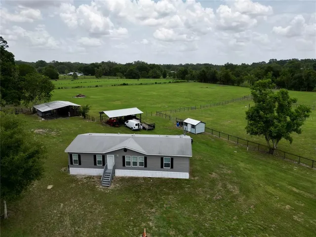 an aerial view of a house with pool big yard and a large tree
