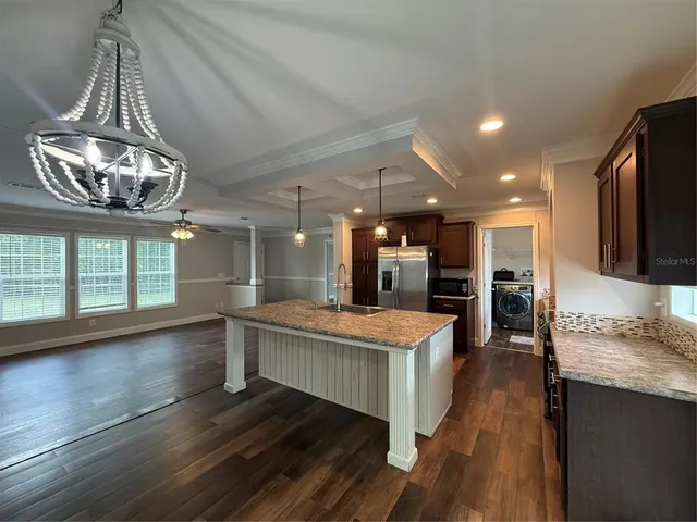 a kitchen with kitchen island a counter top space appliances and a ceiling fan