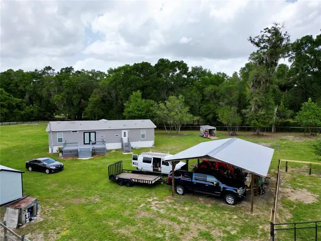 an aerial view of a house with swimming pool garden and trees