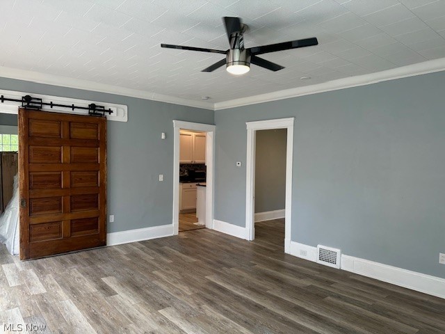 1388 Brookline Road Cleveland, OH 44121 - Photo 6 of 30 Unfurnished bedroom featuring a barn door, hardwood / wood-style flooring, ornamental molding, and ceiling fan