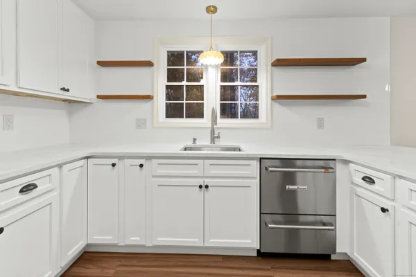 a kitchen with stainless steel appliances white cabinets and wooden floor