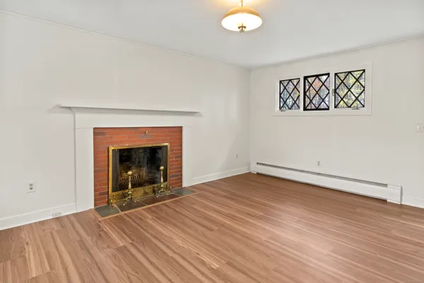 a view of empty room with wooden floor and fireplace