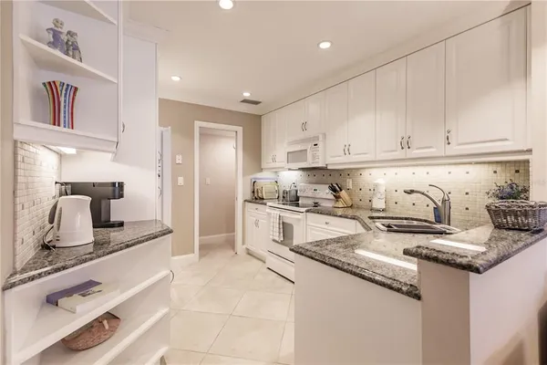 a kitchen with granite countertop a sink stove and cabinets