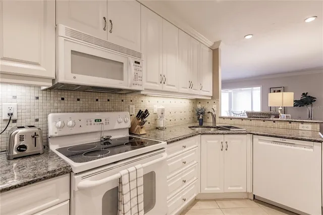 a kitchen with granite countertop white cabinets and white appliances