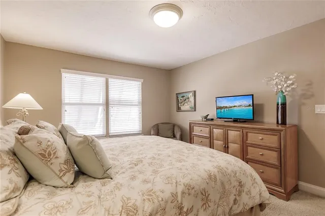 a bedroom with a large bed and a flat tv screen on dresser