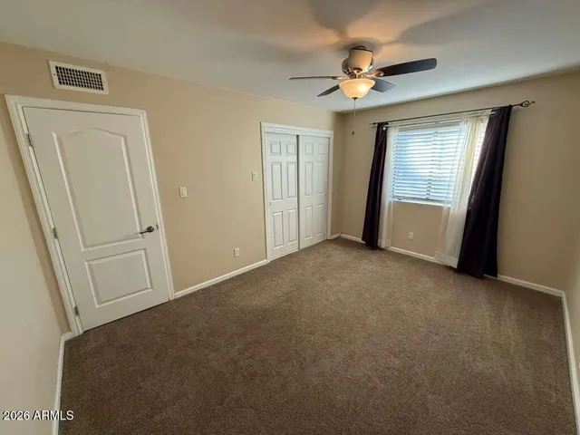 an empty room with windows and fan