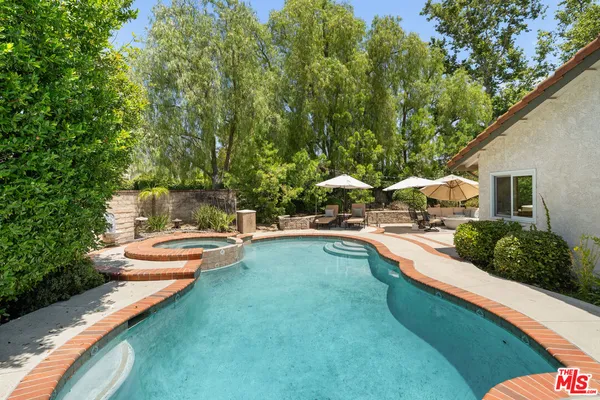 a view of swimming pool with lawn chairs under an umbrella