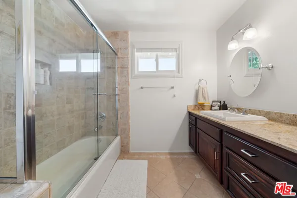 a bathroom with a granite countertop sink a mirror and a bathtub