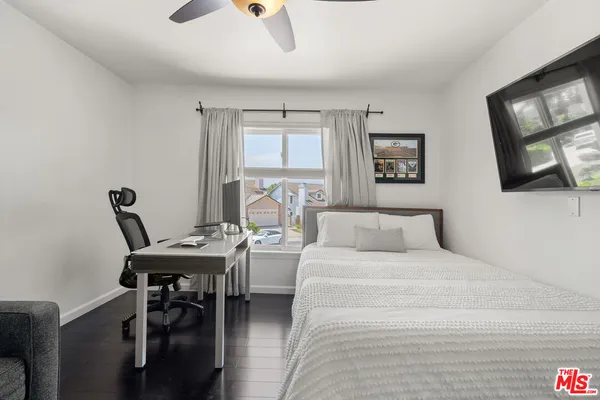 a bedroom with a bed a computer on the desk and chair