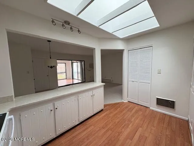 a large white kitchen with a dishwasher and wooden floor