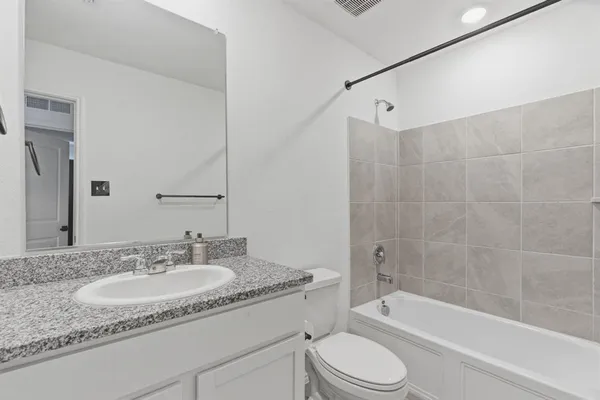 a bathroom with a granite countertop sink toilet tub and shower