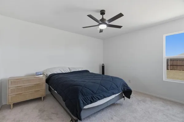 a bedroom with a bed a ceiling fan and a window