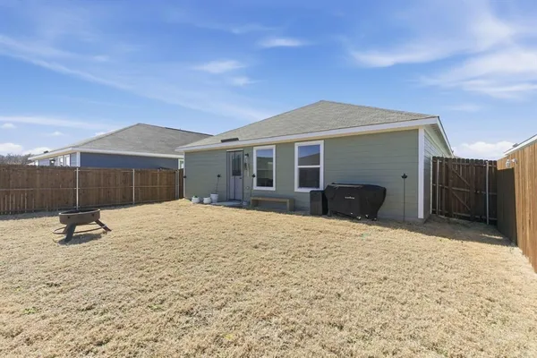 a backyard of a house with wooden fence and a bench